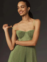 Modella sorridente in abito verde plissettato, spalline sottili, sfondo scuro. Moda elegante, abbigliamento femminile, tendenze 2023.